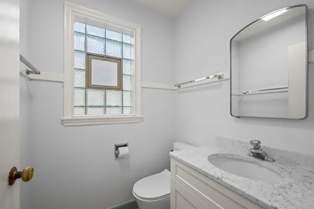 a bathroom with a granite countertop toilet sink and mirror
