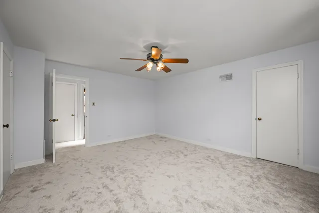 a view of an empty room and chandelier fan