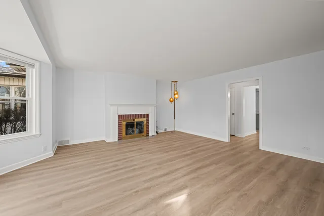 a view of empty room with wooden floor and fireplace