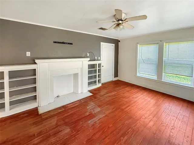 a view of an empty room with a window and wooden floor