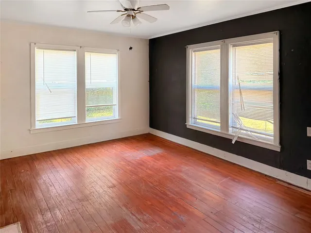 an empty room with wooden floor and windows