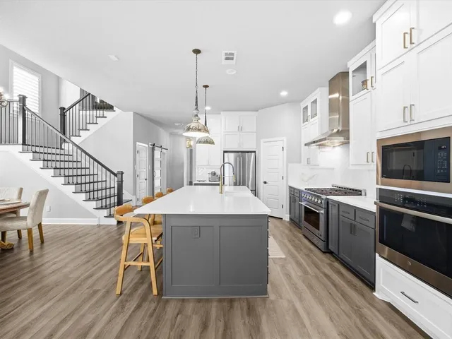 a large kitchen with kitchen island granite countertop lots of white cabinets appliances and furniture