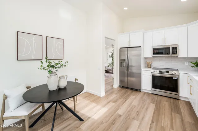 a kitchen with stainless steel appliances a dining table chairs microwave and refrigerator