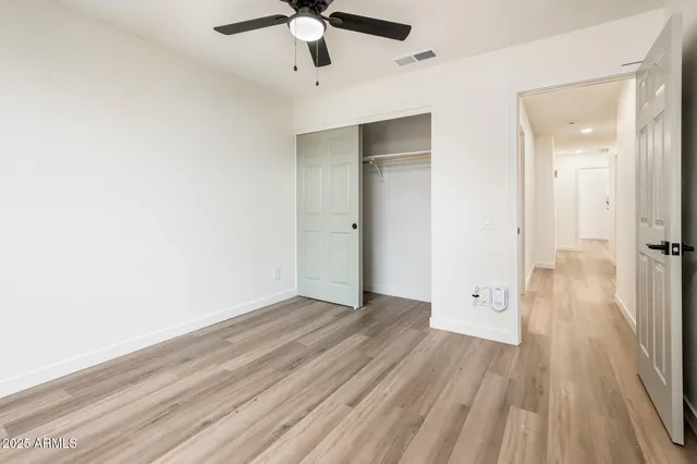 an empty room with wooden floor and a ceiling fan