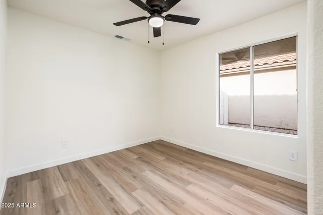 an empty room with a window and ceiling fan