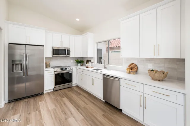 a kitchen with a sink white cabinets and stainless steel appliances