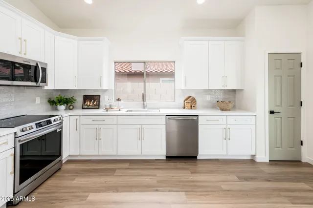 a kitchen with a stove white cabinetry a sink and dishwasher with wooden floor