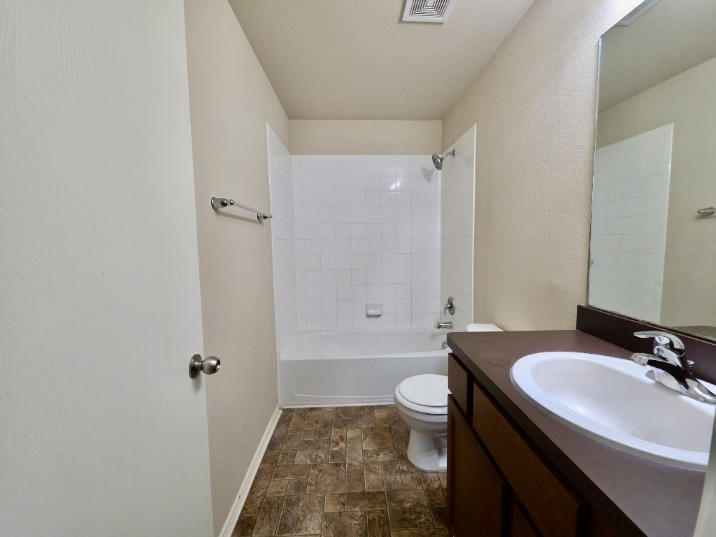 809 Yabers Court Austin, TX 78725 - Photo 24 of 29 Full bathroom with stone finish flooring, vanity, shower / bath combination, and a textured wall