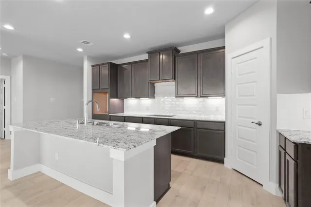 a kitchen with kitchen island granite countertop a sink stove and refrigerator