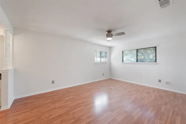 an empty room with wooden floor and windows