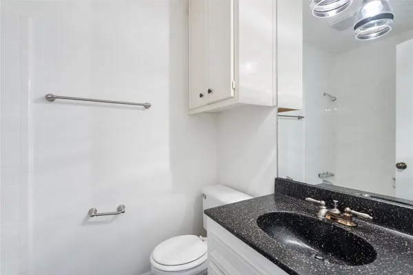 a bathroom with a granite countertop sink toilet and a mirror