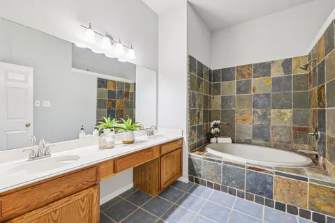 a bathroom with a double vanity sink a mirror and a bathtub