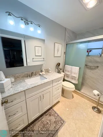 a bathroom with a granite countertop toilet sink and mirror