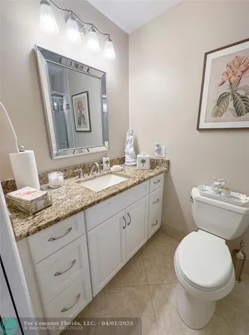 a bathroom with a granite countertop toilet sink and mirror