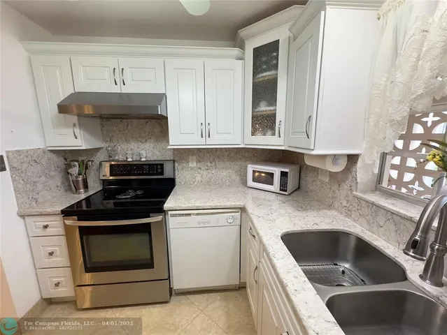 a kitchen with granite countertop a stove sink and cabinets