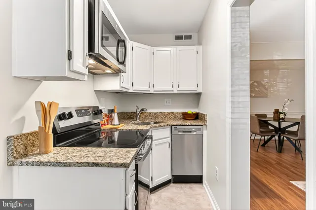 a kitchen with stainless steel appliances granite countertop a stove a sink and a white cabinets