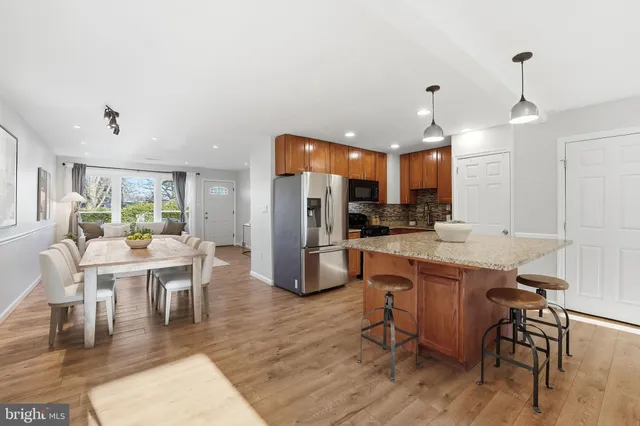 a kitchen with stainless steel appliances kitchen island granite countertop a table chairs and a refrigerator