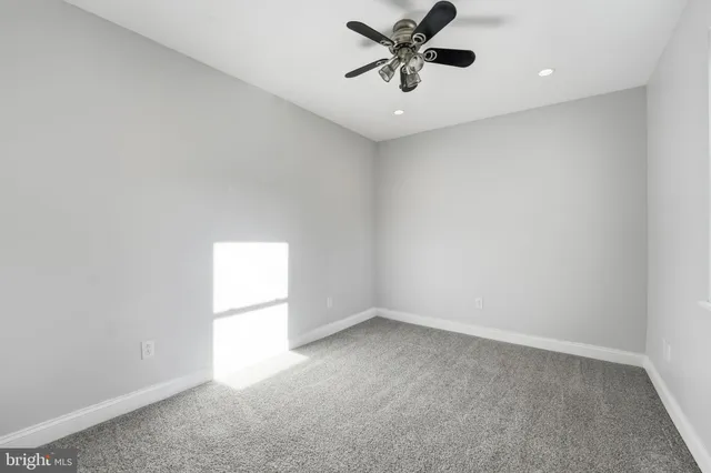 an empty room with a window and a fan