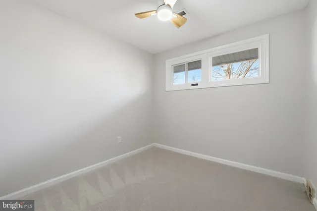 an empty room with a window and a ceiling fan