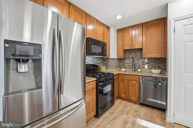 a kitchen with stainless steel appliances granite countertop a refrigerator stove and sink