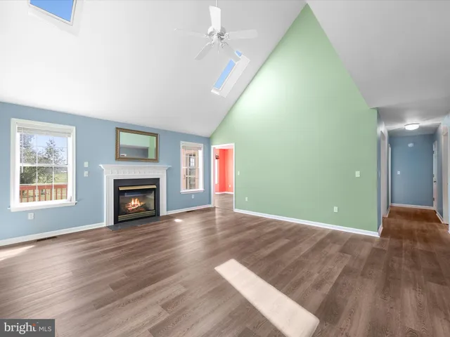 an empty room with wooden floor fireplace and windows