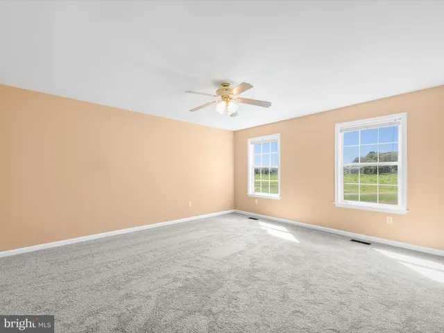 an empty room with a window and a ceiling fan