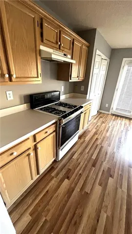 a kitchen with wooden floor and a stove top oven