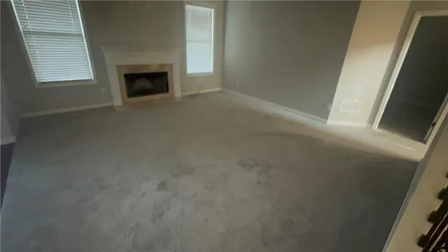 a view of an empty room with a fireplace and a window