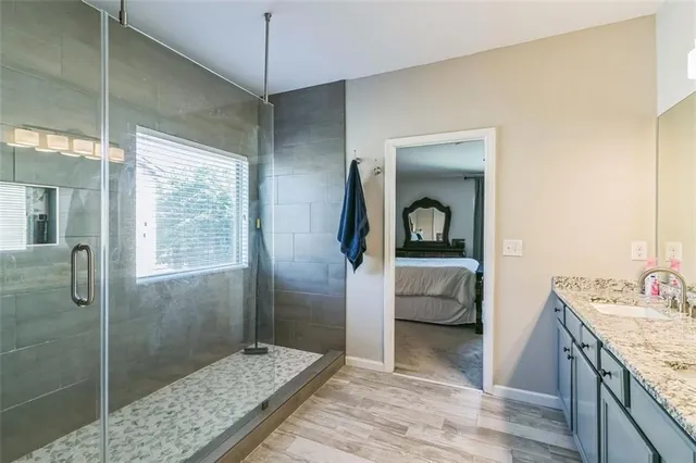 a bathroom with a granite countertop sink a mirror and shower