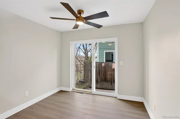 an empty room with wooden floor and a ceiling fan