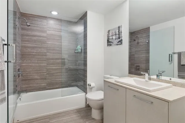 a bathroom with a bathtub shower sink vanity and toilet