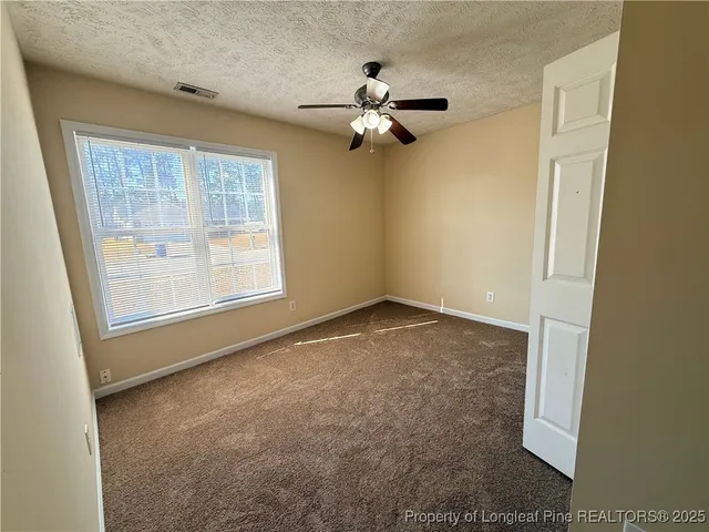 an empty room with windows and fan