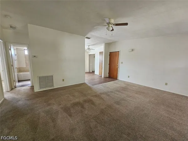 a view of a big room with windows and ceiling fan