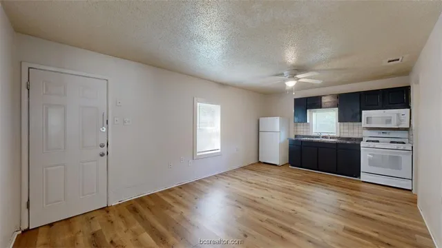 a kitchen with stainless steel appliances granite countertop a refrigerator a sink dishwasher a stove and white countertops with wooden floor