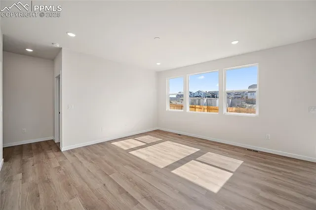 a view of an empty room with window and wooden floor