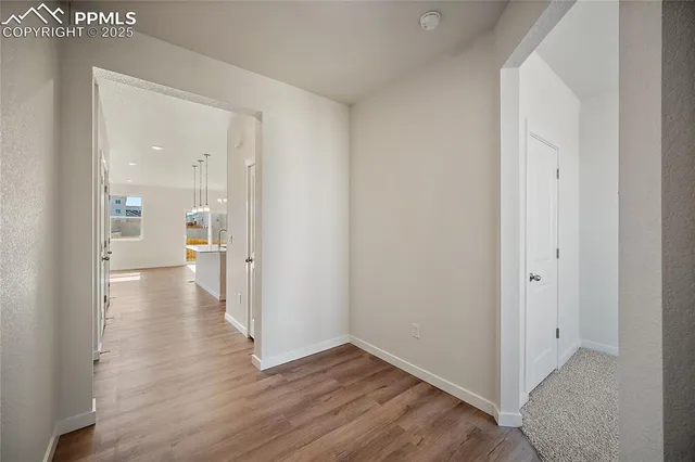 a view of a hallway with wooden floor a bathroom and a sink