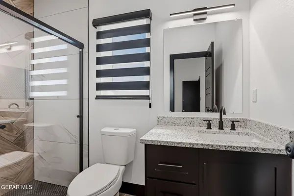 a bathroom with a granite countertop sink toilet and shower