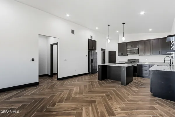 a kitchen with stainless steel appliances kitchen island granite countertop a refrigerator and a sink