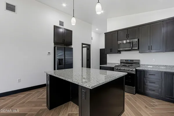 a kitchen with stainless steel appliances granite countertop a stove refrigerator and microwave