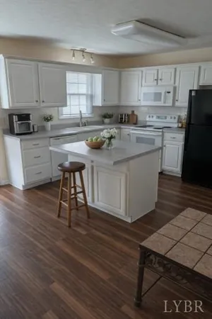 a kitchen with stainless steel appliances granite countertop a stove a sink a refrigerator and white cabinets with wooden floor