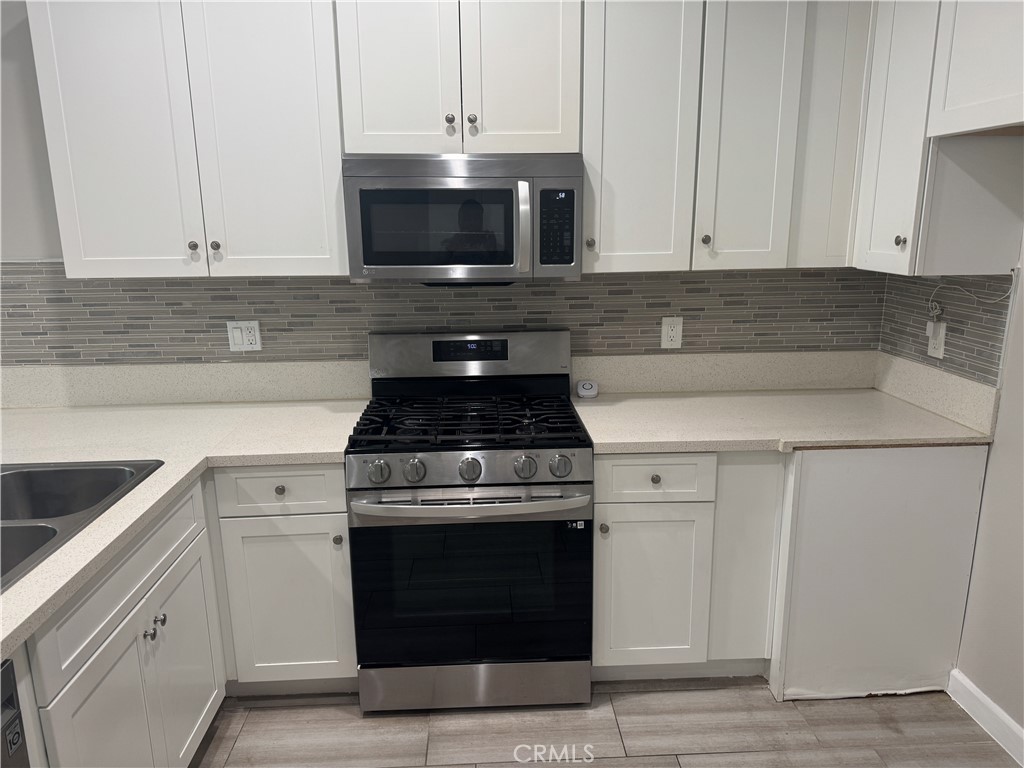 13665 Arrow Route, Unit 3 Fontana, CA 92335 - Photo 8 of 32 a kitchen with white cabinets and black appliances