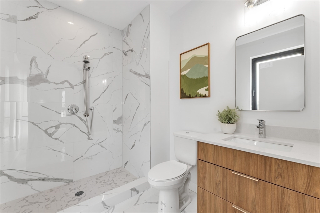 3992 Washington Street, Unit 302 Boston, MA 02131 - Photo 7 of 29 a bathroom with a toilet sink and mirror