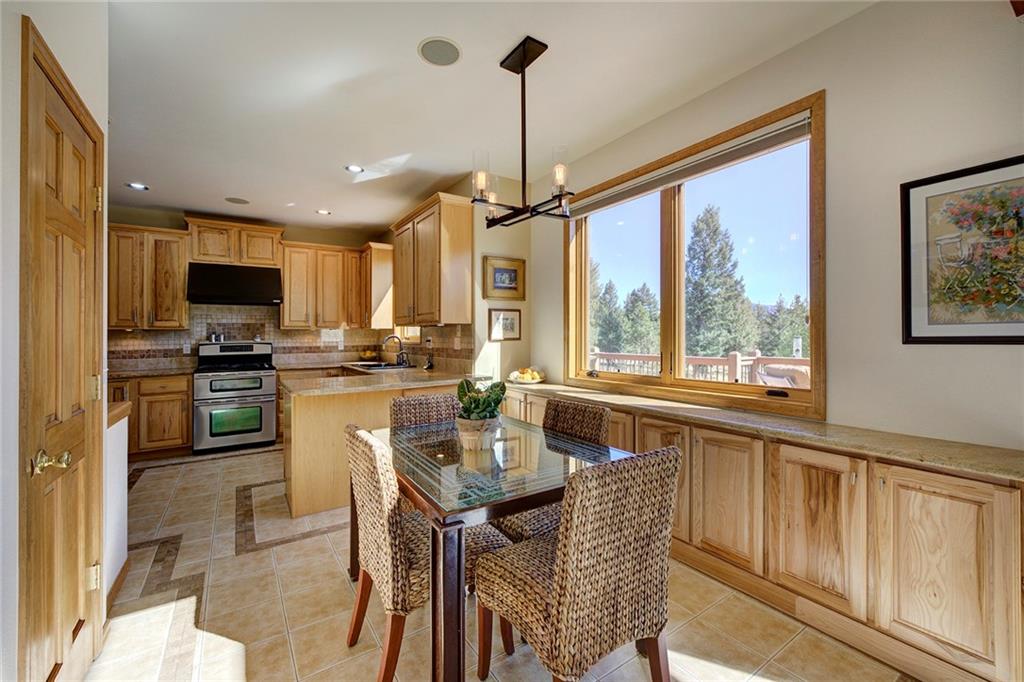 78 Double Tree Road Bailey, CO 80421 - Photo 11 of 34 a kitchen with stainless steel appliances granite countertop a stove top oven a sink dishwasher a dining table and chairs with wooden floor