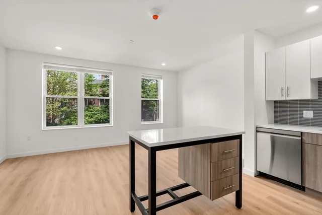 a view of an empty room with window wooden floor and cabinet