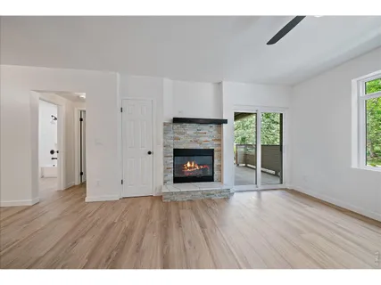 a view of an empty room with wooden floor fireplace and a window