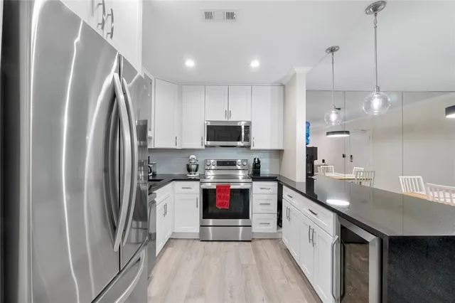 a kitchen with kitchen island granite countertop a refrigerator a sink and a stove