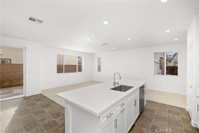 a kitchen with stainless steel appliances a sink dishwasher a stove top oven a refrigerator with white cabinets and wooden floor