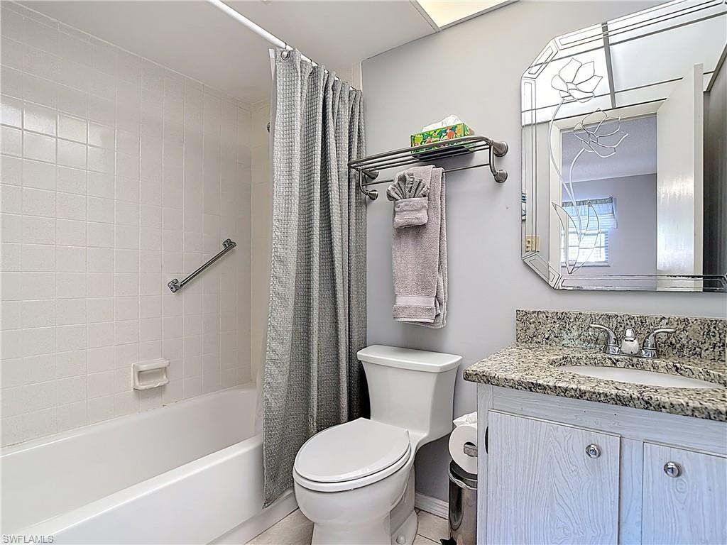 200 Turtle Lake Court, Unit 109 Naples, FL 34105 - Photo 24 of 37 a bathroom with a granite countertop toilet sink and mirror