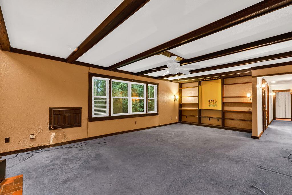 4409 Newton Road Northeast Newark, OH 43055 - Photo 24 of 87 • Blue carpet • Tan painted walls with accent wall • Decorative ceiling beams • Lighted ceiling fan • Woodburning stove with brick hearth • Built-in shelves