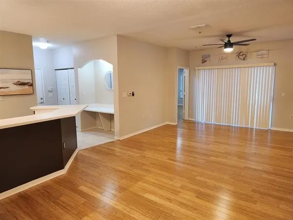 a view of kitchen and empty room with wooden floor